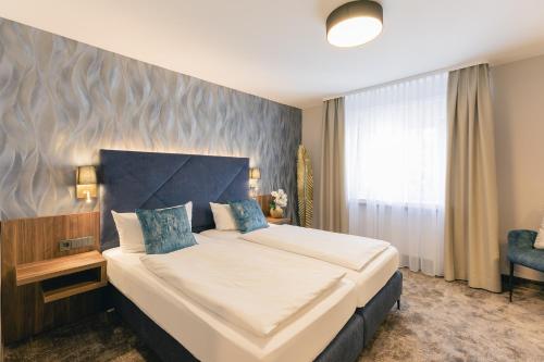 a bedroom with a large bed and a blue wall at Hotel & Restaurant Rose in Bietigheim-Bissingen