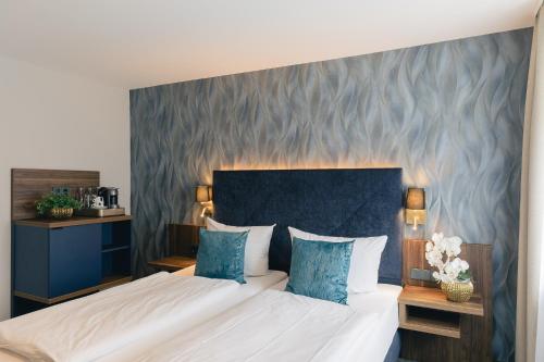 a bedroom with a large bed with a blue headboard at Hotel & Restaurant Rose in Bietigheim-Bissingen