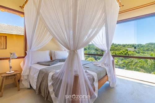 um quarto com uma cama de dossel e uma grande janela em Casa c/ jacuzzi prox a praias em Trancoso SMS001 em Porto Seguro