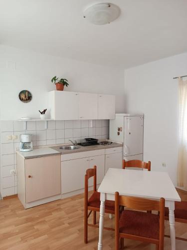a kitchen with white cabinets and a table and chairs at Apartment Udovičić Center in Vodice