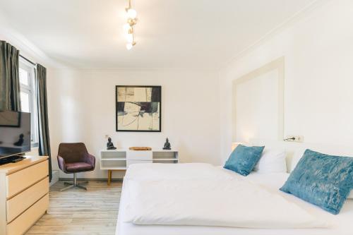 a white bedroom with a bed and a desk at Hotel & Restaurant Rose in Bietigheim-Bissingen