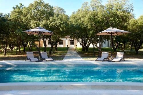 un groupe de chaises et de parasols à côté d'une piscine dans l'établissement Élégance et simplicité au cœur des vignes, à Visan