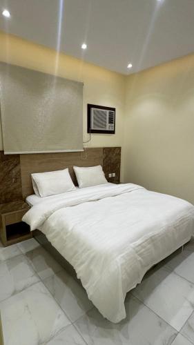 a bedroom with a large bed with white sheets at دانه القحطاني للوحدات السكنية in Tabuk