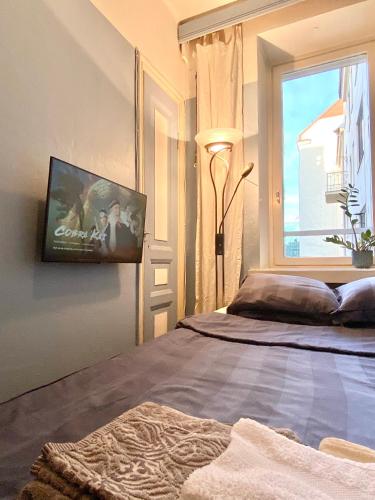 a bedroom with a bed with a tv on the wall at Yksityinen huone ja kylpyhuone kaupungin keskustassa in Helsinki
