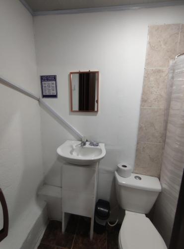 a white bathroom with a toilet and a sink at Cabaña Gaia Rodadero in Santa Marta