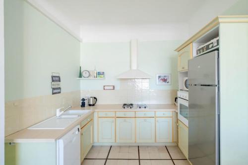 La cuisine blanche est équipée d'un évier et d'un réfrigérateur. dans l'établissement Wonderful 3 bedroom overlooking the old port, à Cannes