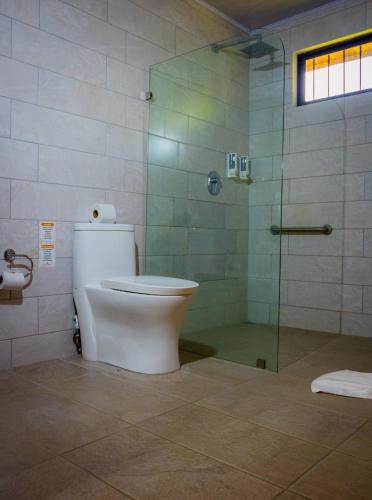 a bathroom with a toilet and a glass shower at Miradas Arenal Hotel & Hotsprings in Fortuna