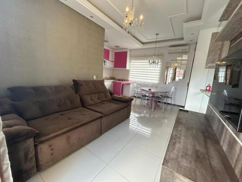 ein Wohnzimmer mit einem braunen Sofa und einem Tisch in der Unterkunft Apartamento inteiro muito aconchegante in Joinville