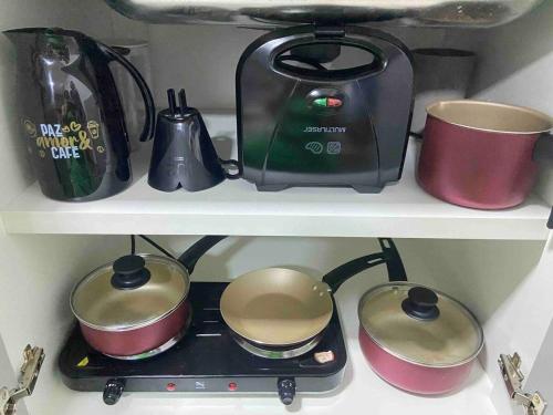 a stove with pots and pans on a shelf at Monte Carmel in Ribeirão Preto