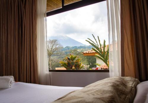 a bedroom with a window with a view of a mountain at Miradas Arenal Hotel & Hotsprings in Fortuna