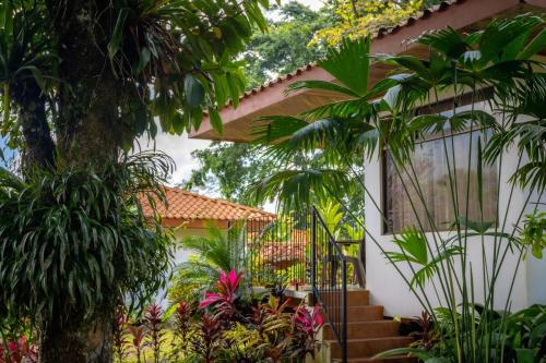 a garden with trees and plants in front of a house at Miradas Arenal Hotel & Hotsprings in Fortuna