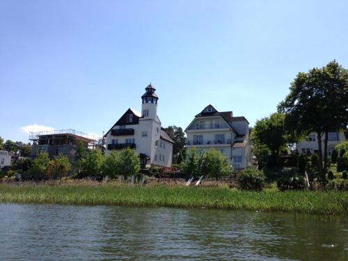 a house with a lighthouse next to a river at Röblinseeterrassen in Fürstenberg-Havel