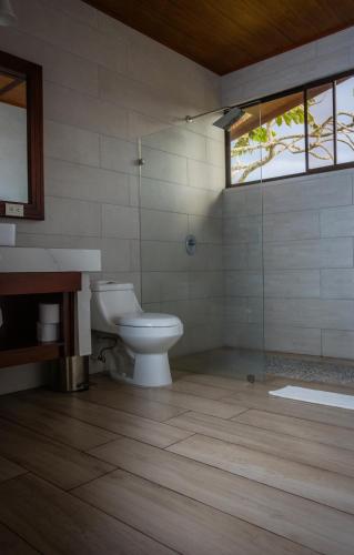 a bathroom with a toilet and a glass shower at Miradas Arenal Hotel & Hotsprings in Fortuna
