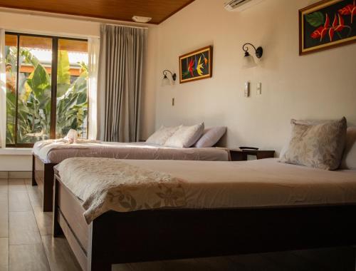 two beds in a room with a window at Miradas Arenal Hotel & Hotsprings in Fortuna
