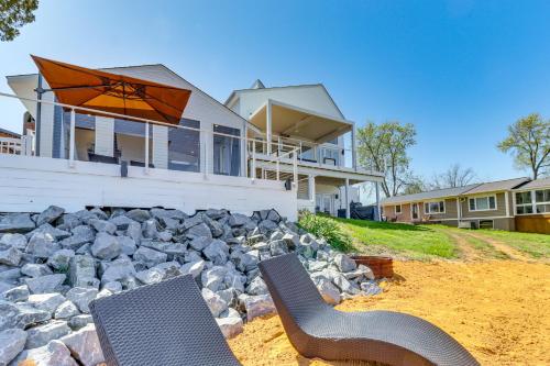 two chairs and an umbrella in front of a house at Waterfront Colonial Beach Studio with Boat Dock! in Colonial Beach