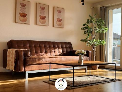 a brown leather couch in a living room with a table at Family M Apartments 21-22 in Sempach