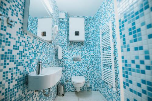 bagno piastrellato blu con lavandino e servizi igienici di Basilica hotel - made for fun! a Novalja (Novaglia)