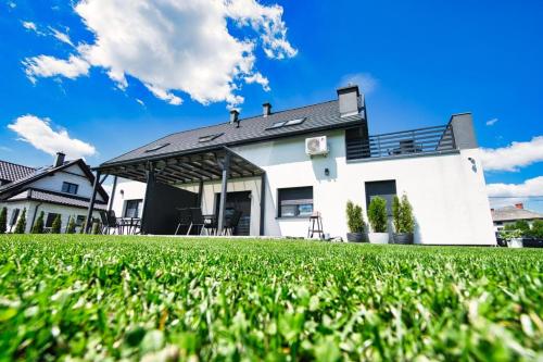 a white house with a green lawn in front of it at Apartamenty Izabell by Housine in Zator