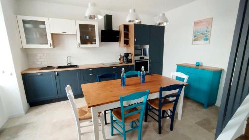 une cuisine avec une table en bois et des armoires bleues dans l'établissement Maison Ker Losa à Saint Guénolé proche plage Pors Carn, à Penmarcʼh