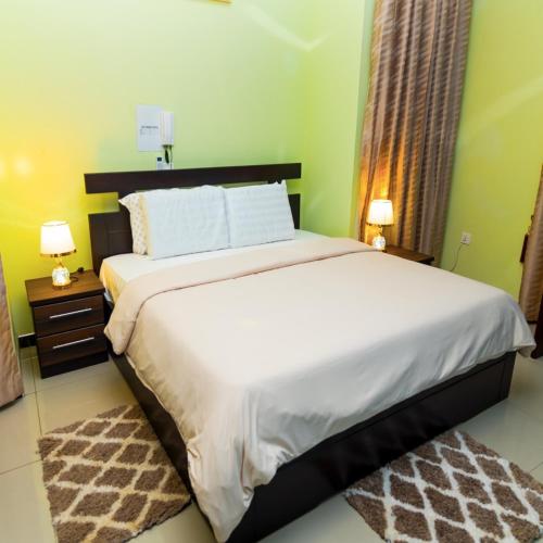 a bedroom with a large bed with two lamps and a rug at MT Everest Hotel Ghana in Kwabenyan