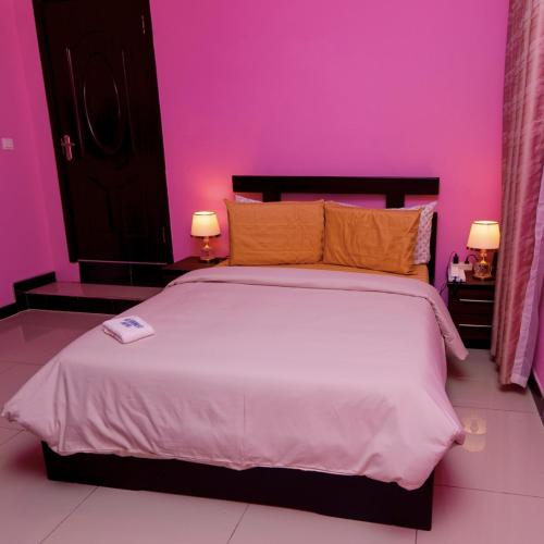 KwabenyaにあるMT Everest Hotel Ghanaのピンクの壁のベッドルーム1室(大型ベッド1台付)