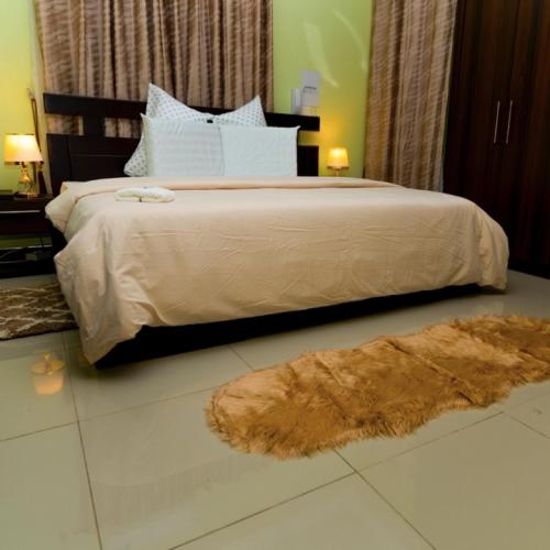 a bedroom with a large bed and a brown rug at MT Everest Hotel Ghana in Kwabenyan