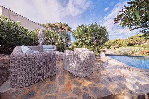 Duas cadeiras de vime sentadas num pátio ao lado de uma piscina em Superbe villa avec piscine et vue mer + Revellata em Calvi