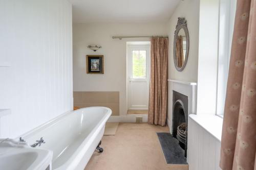 a white bathroom with a tub and a fireplace at Rosemary Cottage in Mortehoe