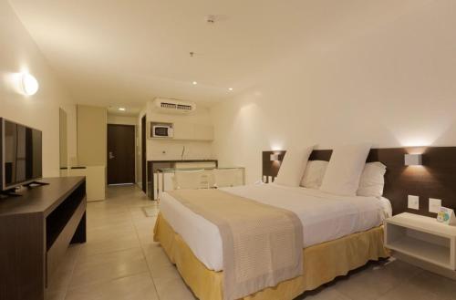 une chambre avec un grand lit et une télévision dans l'établissement Lindo Apto beira-mar no Condomínio do Hotel Ritz Suítes Home Service, à Maceió