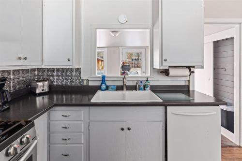a kitchen with white cabinets and a sink at 4th Ave Hideaway - Cozy home with spacious yard in Columbia Falls