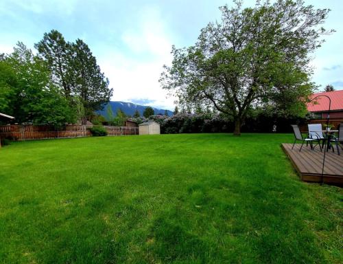 a green yard with a bench in the grass at 4th Ave Hideaway - Cozy home with spacious yard in Columbia Falls
