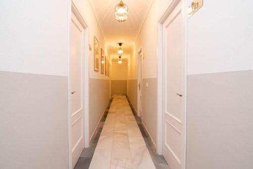 a hallway with white walls and a long hallway at Hostal El Alférez in El Palmar