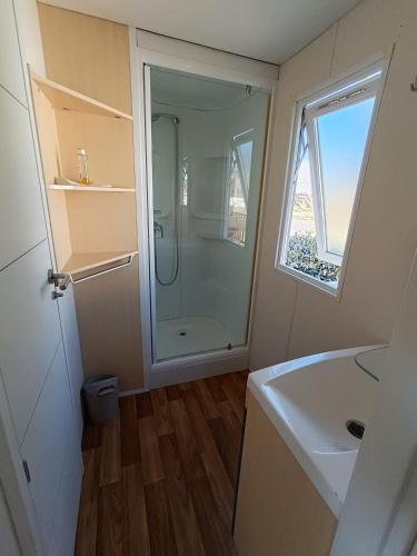 a bathroom with a shower and a sink and a window at MOBIL HOME climatisé camping NOVELA PORT LA NOUVELLE in Port-la-Nouvelle