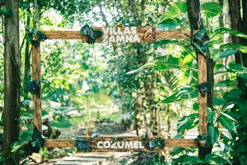 a wooden sign in the middle of a forest at Villas Zamna - Jungle Villas in Cozumel