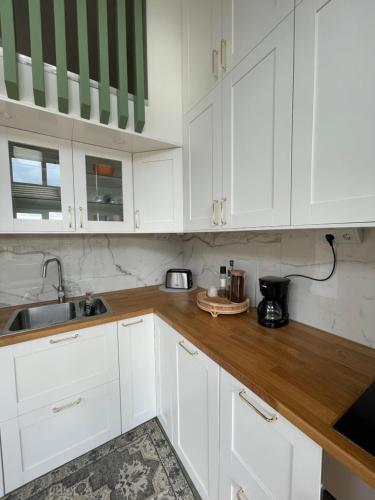 a kitchen with white cabinets and a wooden counter top at Ett nytt fräsch hus utanför Stockholm nära Arlanda in Rosersberg