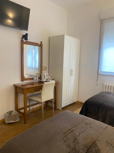 1 dormitorio con escritorio, 1 cama y espejo en Hotel Carabela La Pinta, en Baiona