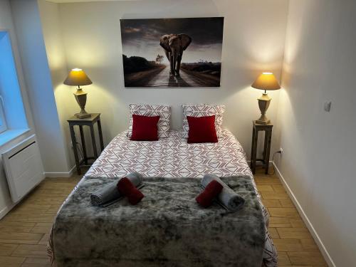 a bedroom with a bed with red pillows and an elephant painting at Nid douceur et douillet Proche Le Pal in Diou