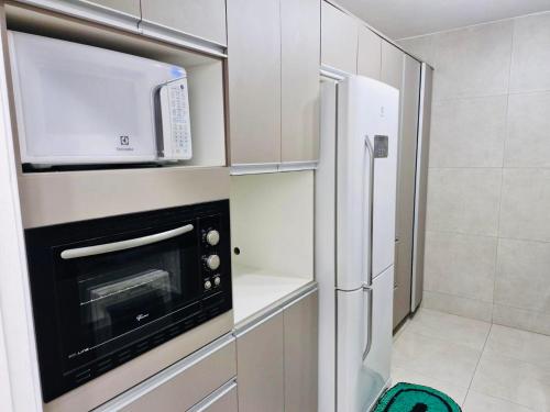 een keuken met een magnetron en een koelkast bij Aconchegante in Campo Grande