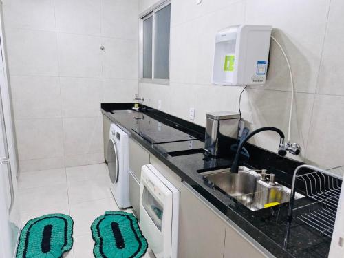 een keuken met een wastafel en een wasmachine bij Aconchegante in Campo Grande