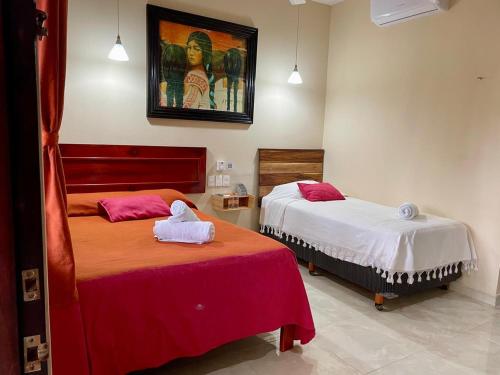 a bedroom with two beds and a painting on the wall at Hotel Nojoch che in Cobá
