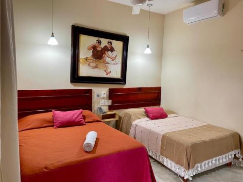 a bedroom with two beds and a painting on the wall at Hotel Nojoch che in Cobá