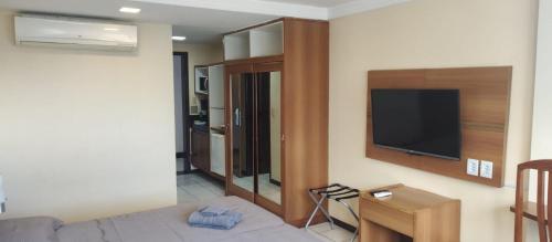 a living room with a bed and a flat screen tv at Nallah ApartHotel in Natal