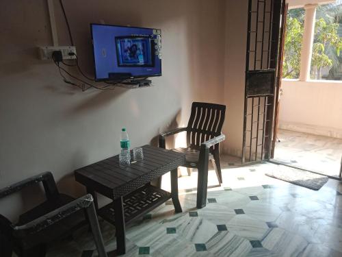 a living room with a table and a tv on a wall at Devka villa in Daman