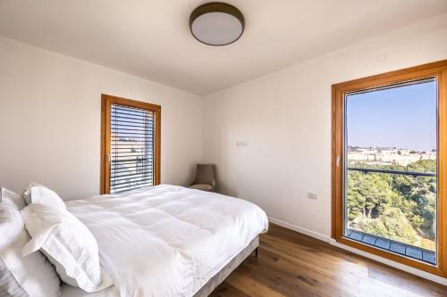 um quarto com uma cama branca e uma grande janela em king david residence 131 em Jerusalém
