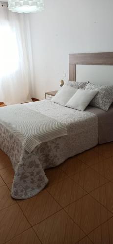 a bedroom with a large bed with a wooden headboard at Piso Sol y Mar vacacional in Moaña