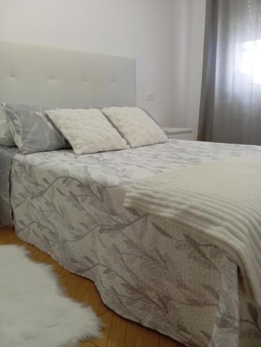 a bed with a blanket and a white rug on the floor at Piso Sol y Mar vacacional in Moaña