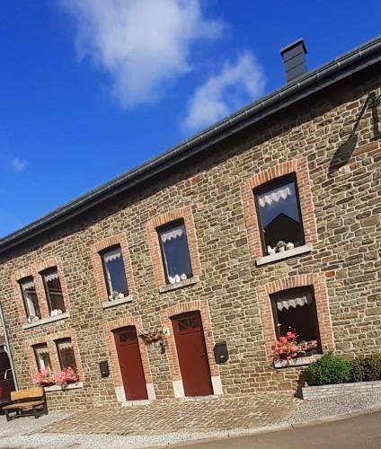 a brick building with windows and flowers on it at Sous Le Même Toit in Rendeux