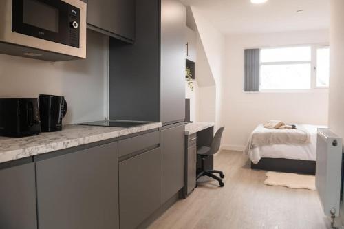 a kitchen with a desk and a bed in a room at Homely Studio: Old Trafford in Manchester