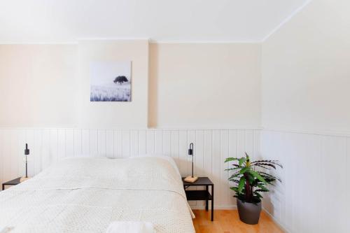 a white bedroom with a bed and a potted plant at Authentic house with playroom and infrared sauna in Bilzen