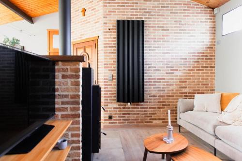a living room with a couch and a brick wall at Authentic house with playroom and infrared sauna in Bilzen